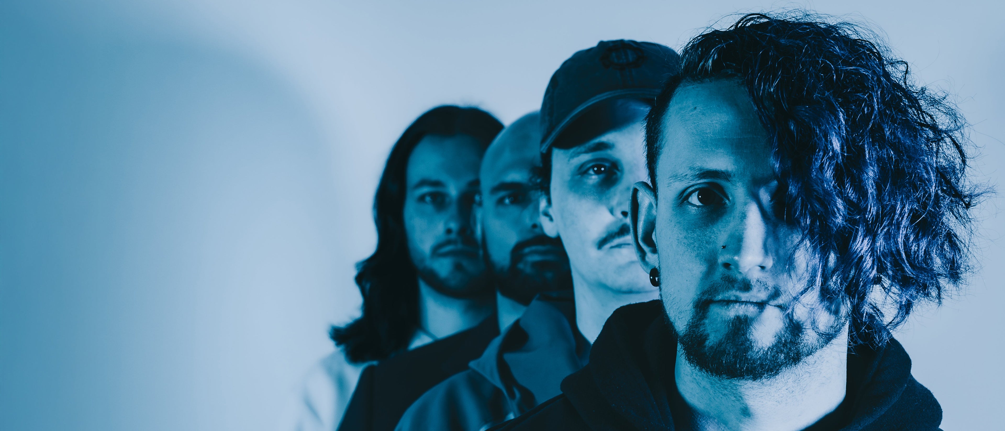 Four individuals standing close together with a blue filter applied